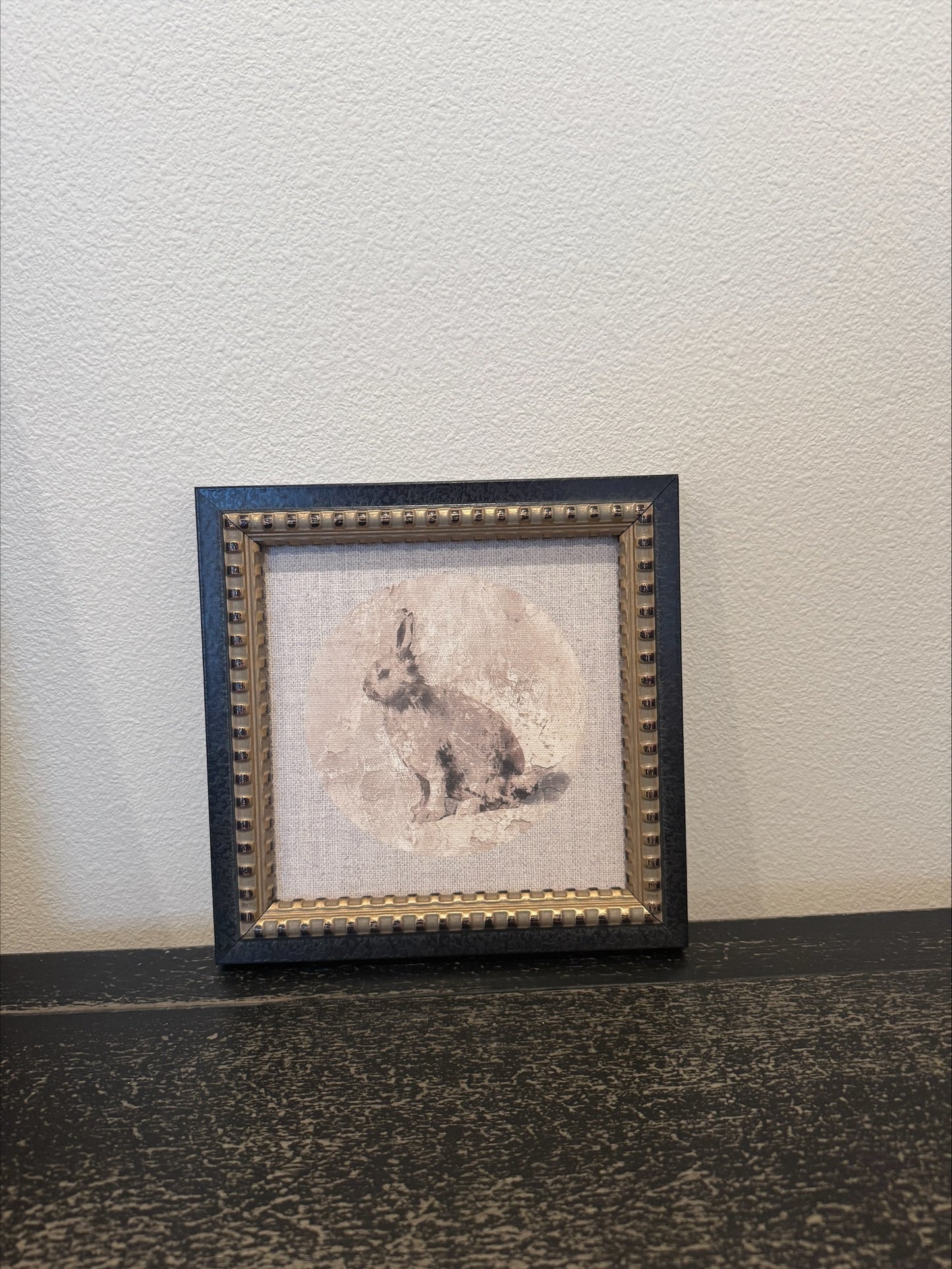 Framed artwork of a rabbit on a textured wall